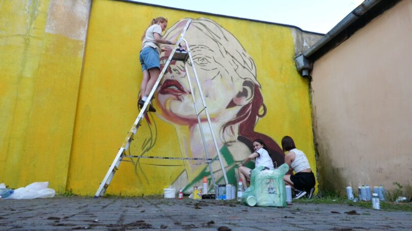 Уличные художники рисуют картины на стенах